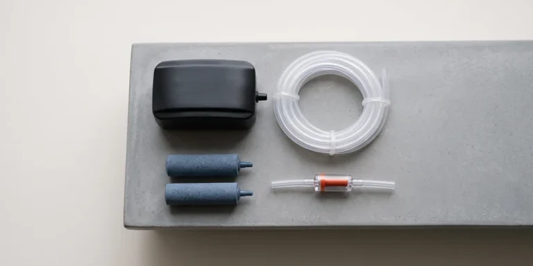 Air pump, tubing, air stones and check valve laid out on a grey surface